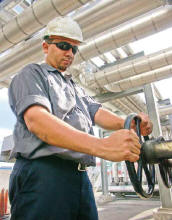 Eric Mendez adjusts a valve adding virgin liquid asphalt to the PMA mixing tank. (Photo by Carl Thiemann)